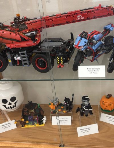 A display of LEGO models including a crane and motorcycle.
