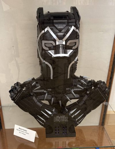 LEGO sculpture of a superhero mask and crossed arms, in black and silver.
