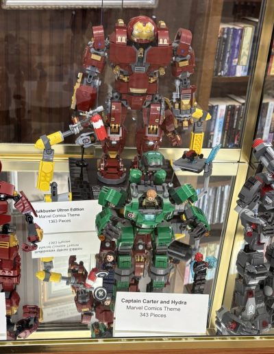 LEGO Marvel models displayed in a glass cabinet with four different figures. Hulkbuster Smash Marvel Comics Theme 248 Pieces Hulkbuster Ultron Edition Marvel Comics Theme 1363 Pieces Captain Carter and Hydra Marvel Comics Theme 343 Pieces War Machine Buster Marvel Comics Theme 362 Pieces